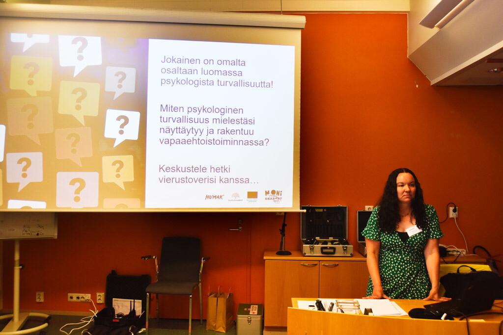 Annika Harsu luennoi, valkokankaalle on heijastettu ryhmätyöskentelyn kysymykset. 