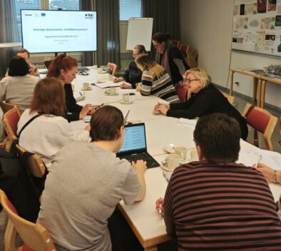 Kokouspöydän ääressä työskentelee ihmisiä pienryhmissä.